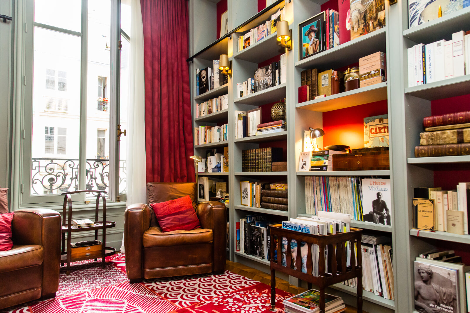Boudoir-bibliothèque à fond rouge, fauteuils club en cuir et fenêtre à rideau rouge, Paris XVII