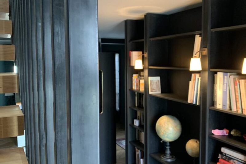 Rangements blancs et verrière métallique, cadres et objets sur un meuble bas