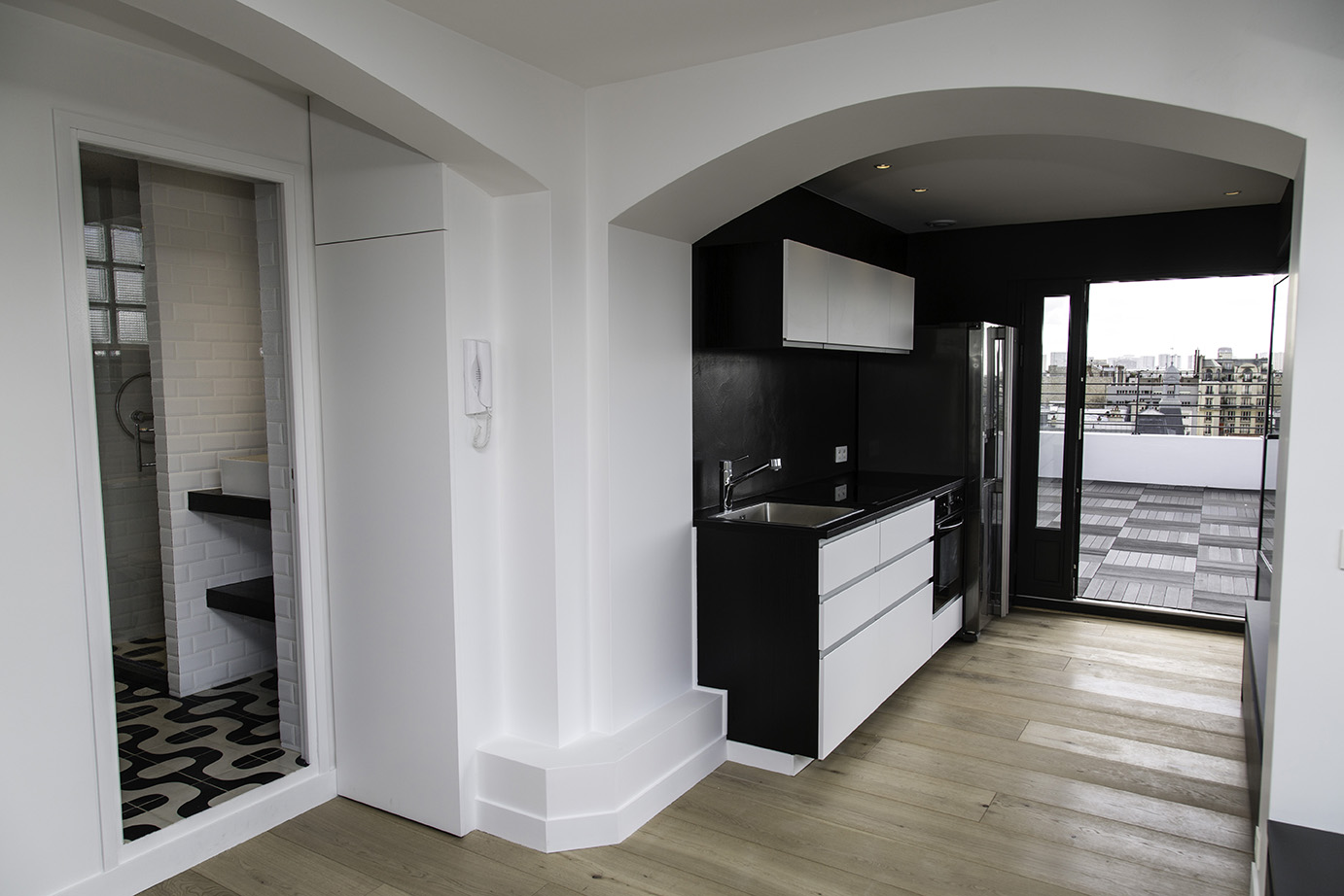 Niveau haut : kitchenette noire ouverte sur la terrasse