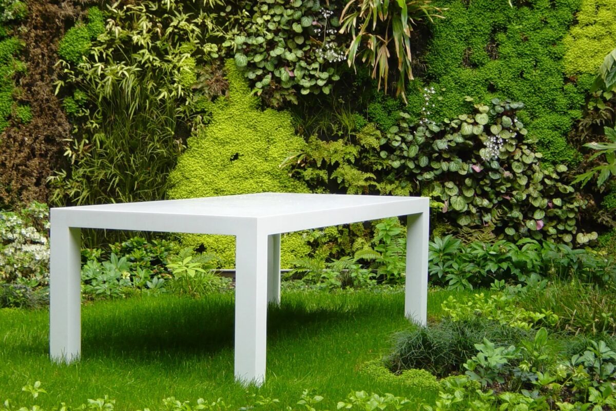 Table blanche dessinée sur mesure devant un mur végétal